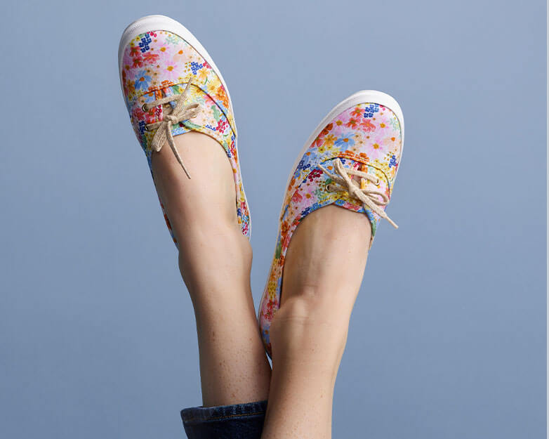 A pair of feet in a pair of Keds shoes from the Rifle Paper Company collection.