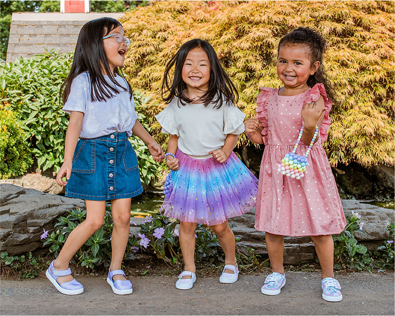 Trois jeunes filles portant des chaussures de la collection enfants.